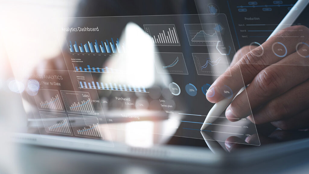 Person looking at tablet that's laying on a desk with a hologram analytics dashboard floats over the tablet