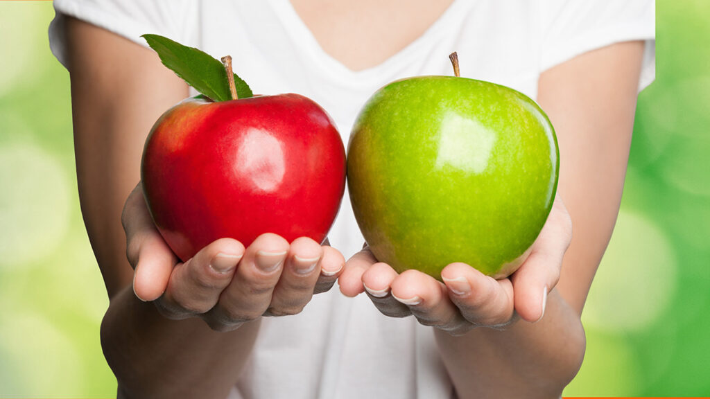 Image of a person holding a red apple and a green apple next to one another