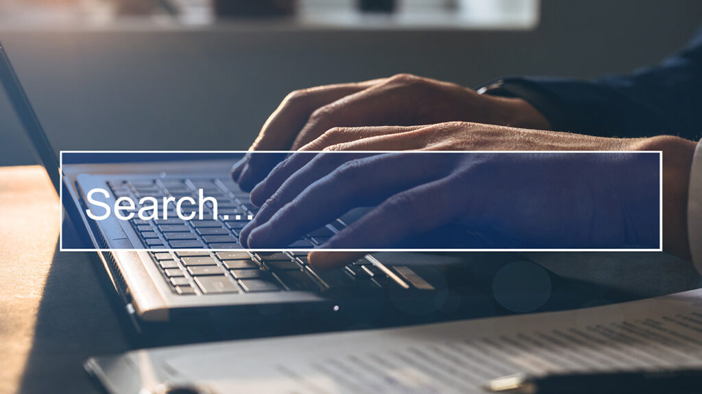 Image of a person typing on a laptop with a transparent search bar above the center of the image